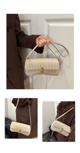 Detail of beige crocodile embossed leather underarm bag with gold cylindrical metal lock