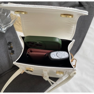 Internal storage view of white leather crossbody bag showing phone, wallet, and lipstick