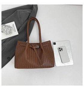 Detail of dark brown woven tote bag with silver buckle and thin handles for commuters