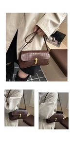 Detail of dark brown faux crocodile baguette bag with gold buckle and slim shoulder strap