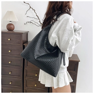 Detail shot of the woven texture and soft leather of this black hobo tote shoulder bag