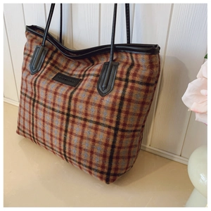 Détail du sac cabas à carreaux montrant la texture tweed avec poignées en cuir et logo