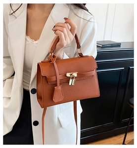 Detail of brown lychee grain leather handbag with gold-tone hardware and top handle strap