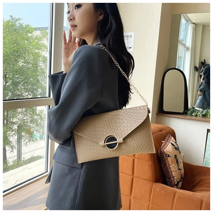 Detail of beige crocodile pattern envelope bag with gold chain and metal buckle