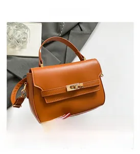 Dettaglio borsa in pelle marrone con chiusura a scatto dorata e texture a grana fine