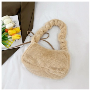 Macro shot of plush beige handbag featuring a twisted woven handle on white fabric