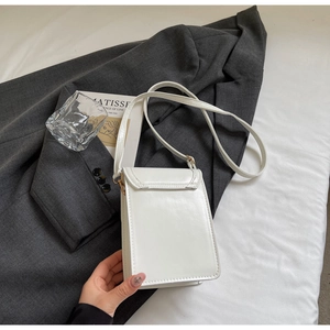 Vertical white glossy leather phone bag shown on a grey blazer in a stylish setting