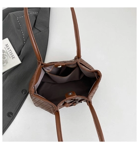 Detailed interior of a brown woven tote bag showing the magnetic closure and pocket