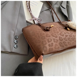 Dettaglio della borsa tote leopardata con cinturini in similpelle marrone e ciondolo in peluche