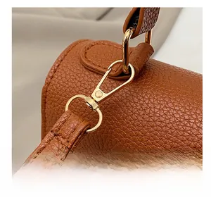 Detail of brown lychee-patterned leather bag with polished gold-tone metal strap hook