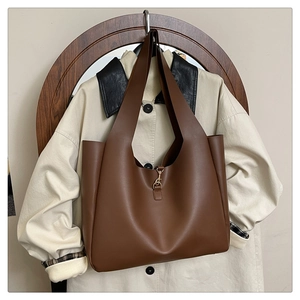 Dettaglio di una borsa tote in pelle marrone con chiusura in metallo dorato e tracolla