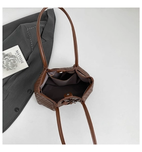 Interior detail of a brown woven tote bag featuring a magnetic buckle and internal pocket