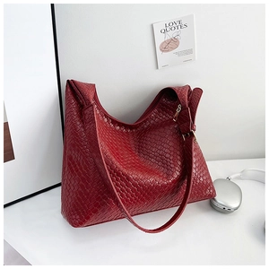 Detailed close-up of dark red woven leather tote bag with premium texture and gold zipper