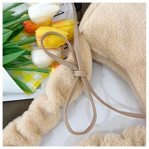 Close-up of soft beige plush handbag texture featuring a synthetic leather bow detail