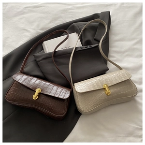 Detail of crocodile-embossed underarm bags in brown and white with gold U-buckle