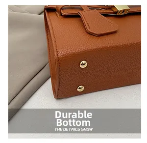 Close-up of brown lychee leather bag bottom with gold protective studs and hardware