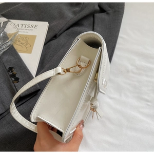Close-up of white leather square bag featuring golden buckle and side knot detail