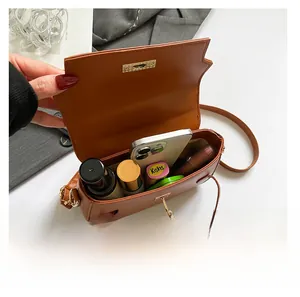 Dettaglio della capacità interna di una borsa a tracolla marrone con oggetti di uso quotidiano