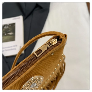 Détail d'un sac besace en daim marron avec franges et rivets dorés polis