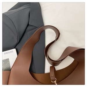 Dettaglio della borsa tote grande in pelle opaca marrone con tracolla sottile e fibbia