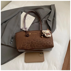 Dettaglio della borsa tote leopardata con logo dorato, tracolla e ciondolo peluche
