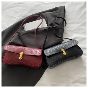 Detail view of crocodile embossed underarm bags in burgundy and black with gold U-shaped buckle