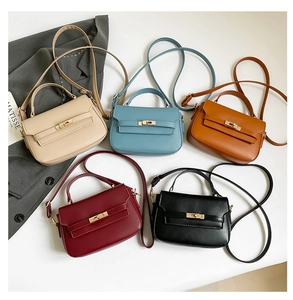 Flat lay of mini crossbody saddle bags in five colors with gold hardware and top handles