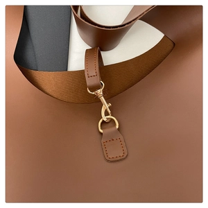 Dettaglio dei ganci dorati e dell'anello a D sulla borsa tote in pelle marrone scuro