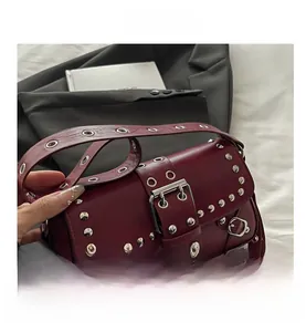 Dettaglio borsa a tracolla bordeaux in pelle con borchie argentate e cinturino con fibbia