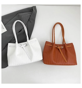 Detail of V-shaped woven texture on leather tote bag with stylish buckle strap design
