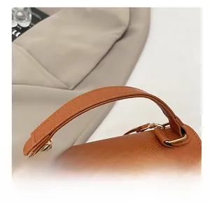 Close-up of brown lychee grain leather handle with metallic buckle on a Kelly bag