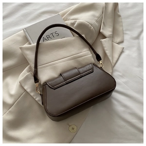 Detailed view of dark brown leather underarm bag with gold hardware and embossed texture
