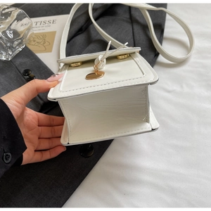 Detail of white glossy mini square bag with gold metal hardware and fine stitching