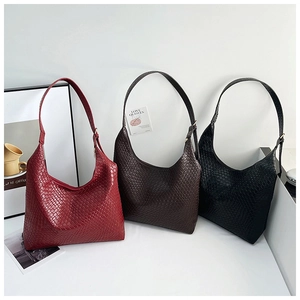Close-up of three woven leather hobo tote bags in wine red, dark coffee, and black