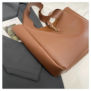 Dettaglio della borsa tote in pelle marrone con fibbia dorata su un blazer grigio