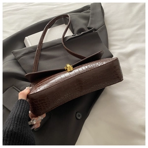 Detail of dark brown crocodile embossed leather texture with gold twist lock closure