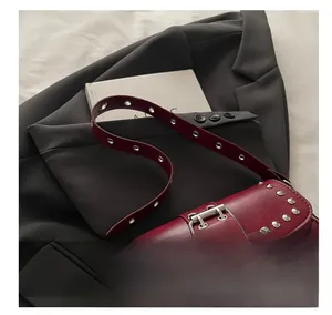 Dettaglio della borsa punk rosso scuro con borchie metalliche e pelle sintetica lucida