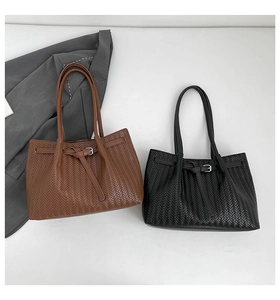Detail of black and brown woven tote bags with buckle accents and long handles