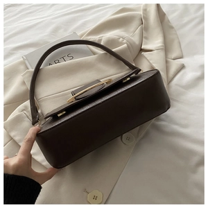 Close-up of dark brown crocodile-embossed leather bag with a gold metal clasp and strap