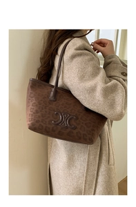 Detailed view of leopard print bucket bag with gold-tone hardware and leather shoulder strap
