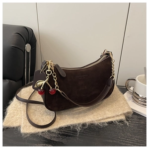 Detail of coffee suede half-moon bag with gold chain and red cherry charm decor