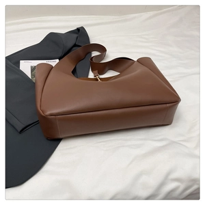 Vista laterale del grande borsa tote marrone in ecopelle con base larga e tracolla
