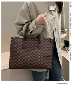 Close-up of brown tote bag featuring M-letter monogram pattern and leather handle