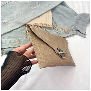 Detail of light brown woven texture crossbody bag with gold chain and black stone buckle