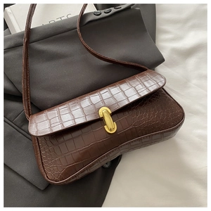 Close-up of brown crocodile texture leather bag with elegant gold U-shaped metal buckle