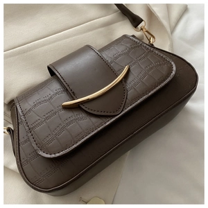 Detail of dark brown crocodile embossed leather bag with gold crescent metal clasp