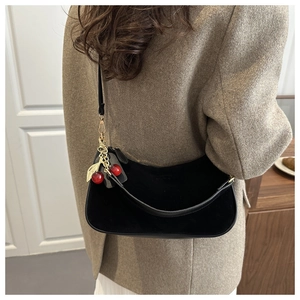 Détail du sac croissant en velours noir avec breloque cerise et garniture dorée