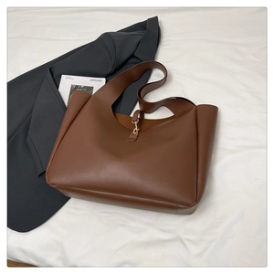Dettaglio della borsa tote in pelle marrone scuro con fibbia in metallo dorato su fondo bianco