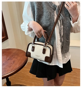 Close-up of the vintage-style handbag featuring contrast piping and fashion brand lettering