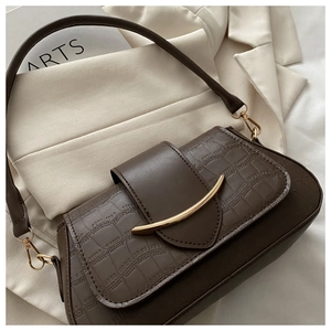 Detailed view of dark brown crocodile embossed leather texture with golden metal trim